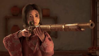 Naoe in Assassin's Creed Shadows aims a golden teppo at someone off-screen indoors.