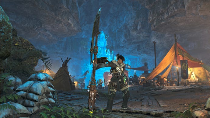 A female hunter in Monster Hunter Wilds poses in front of the camera with their weapon of choice, the Insect Glaive.
