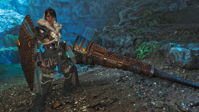 A female hunter in Monster Hunter Wilds poses in front of the camera with their weapon of choice, the Lance.